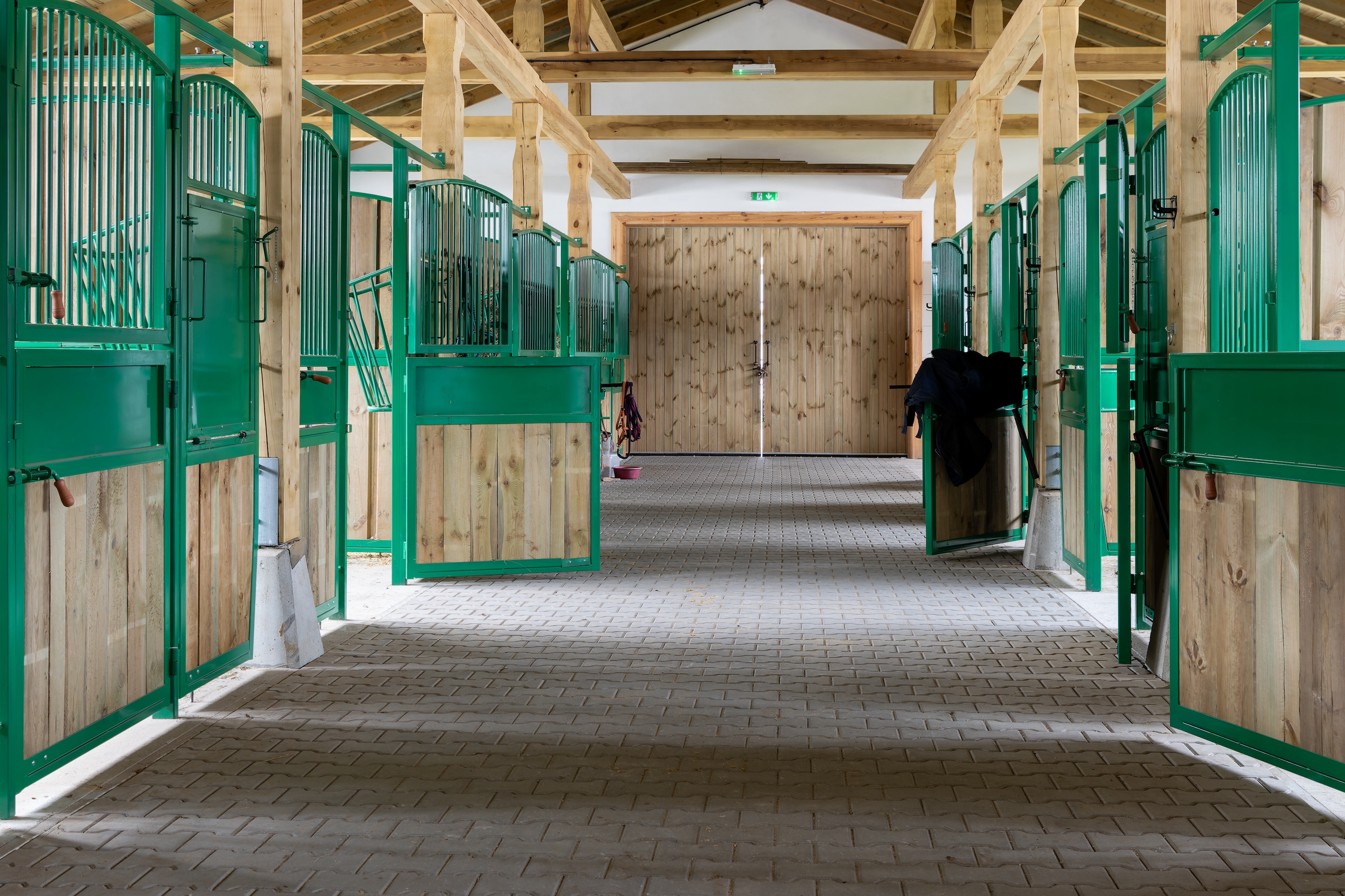 Stallgasse in einem Pferdestall mit grünen Türen